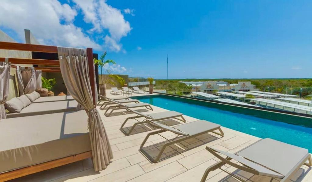 a group of lounge chairs and a swimming pool at New! Modern Escape, Tuk Tierra In Tulum in Tulum