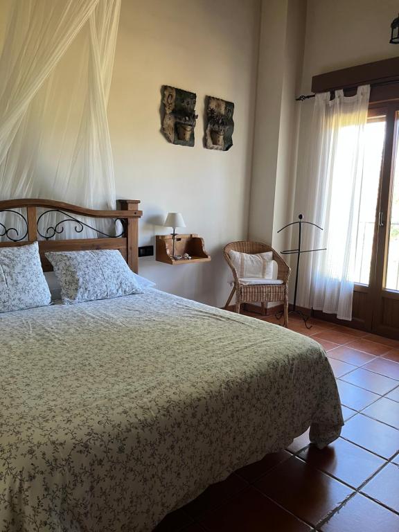 a bedroom with a bed and a chair and a window at Altillo del Aravalle in Umbrías