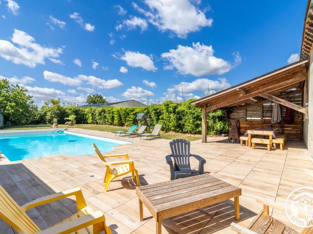 un patio con tavolo e sedie in legno accanto alla piscina di Grande maison à la campagne avec piscine et climatisation - FR-1-622-113 a Chazé-sur-Argos