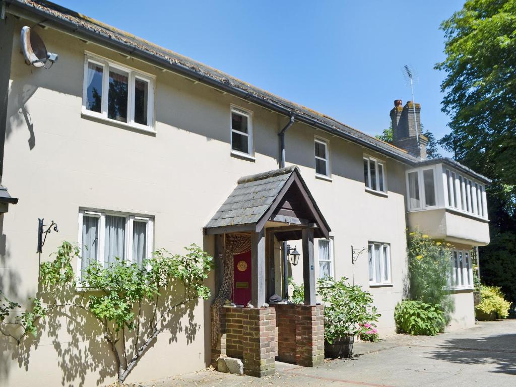 une maison blanche avec un toit en gambrel dans l'établissement Stable Cottage, à Lyminster