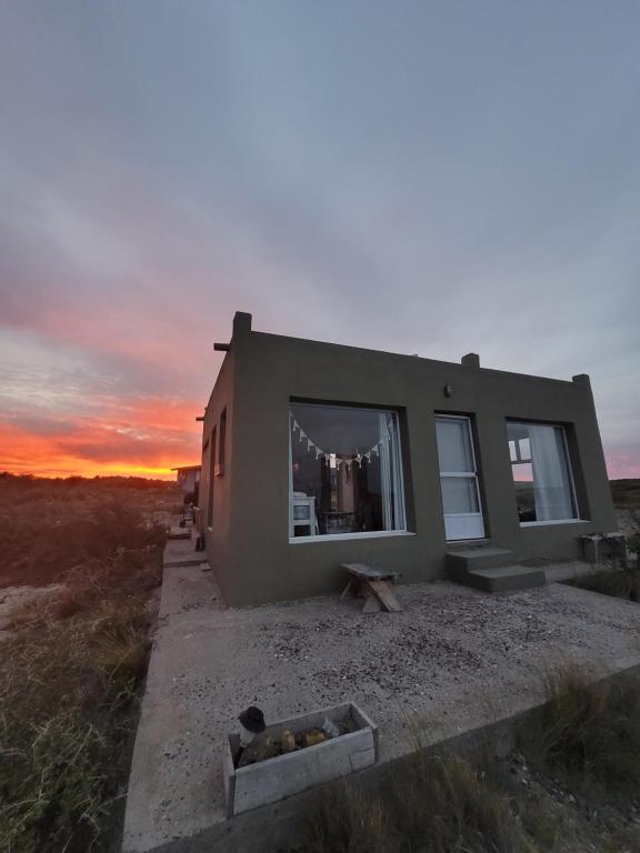 a small house with a sunset in the background at Casa de Mar El Qubito las Grutas in Las Grutas