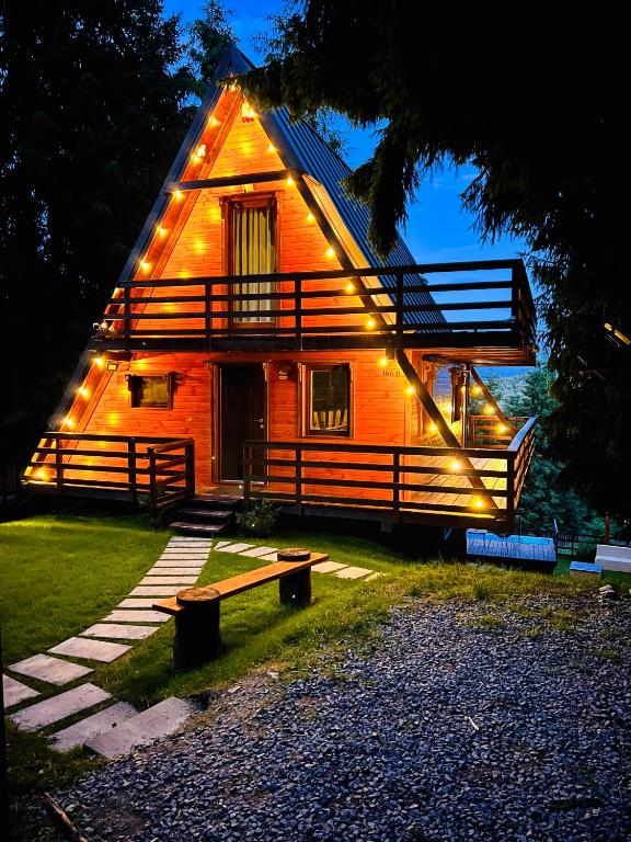 a large wooden house with lights on the side of it at Chalet A Baisoara - Luxury A-Frame cu Piscină Încălzită in Băişoara