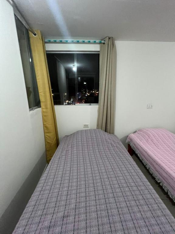 a bedroom with two beds and a window with a view at Centro de Tacna quinto piso in Tacna