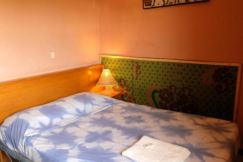 Hotel de la Liberte في واغادوغو: غرفة نوم صغيرة بها سرير ومصباح