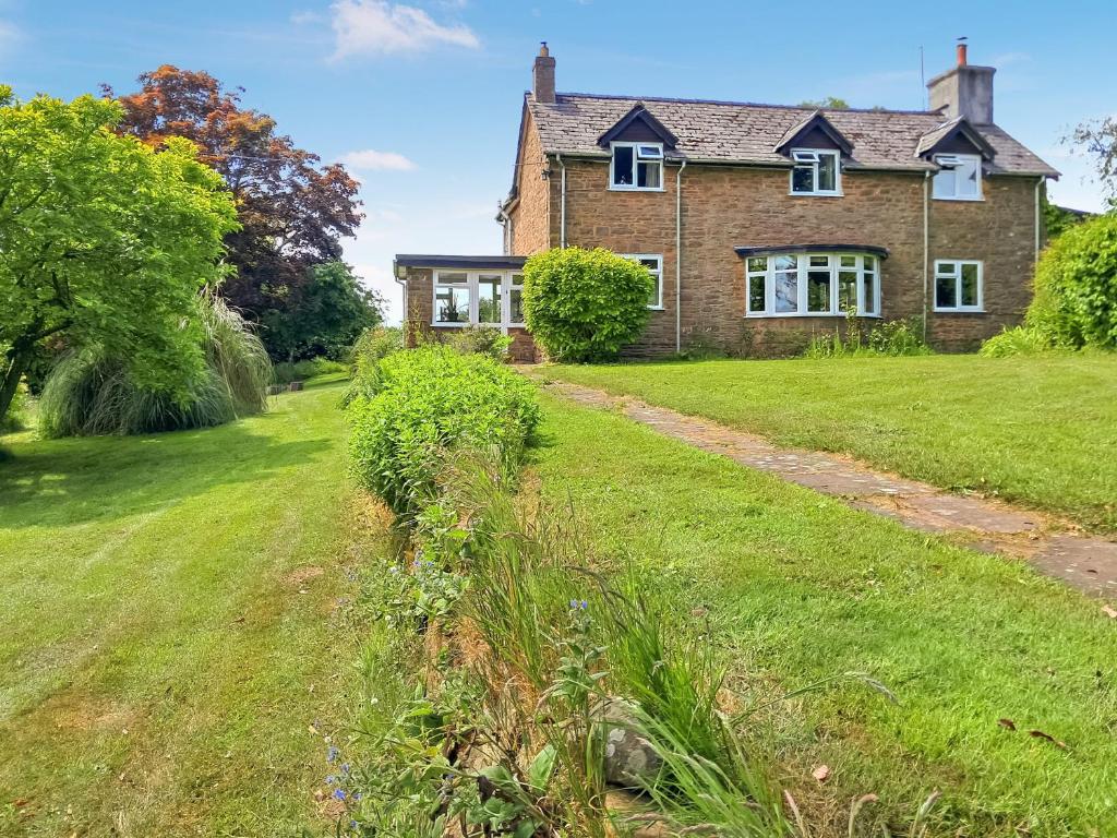 une grande maison en briques avec une cour d'herbe dans l'établissement Keepers Cottage, à Garway