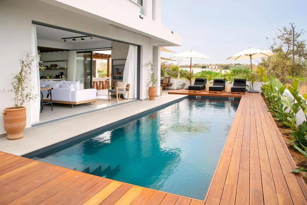 una piscina con terrazza in legno e una casa di Amazing Protaras Villa Villa Lubbock 3 Bedrooms Private Outdoor Pool a Protaras