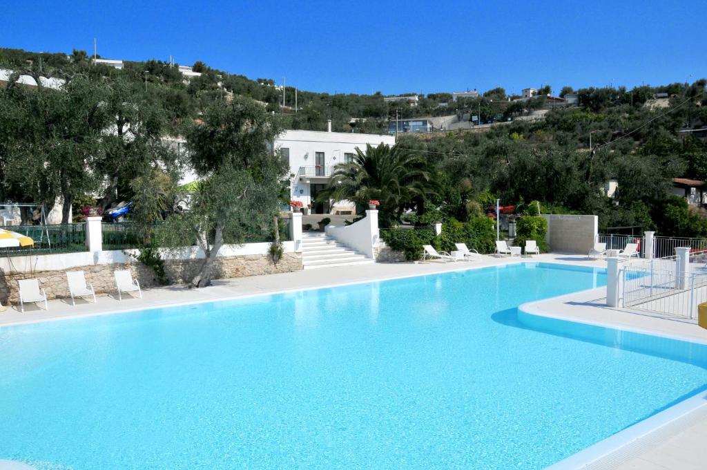 uma grande piscina azul com uma colina ao fundo em Agriturismo Giorgio em Mattinata