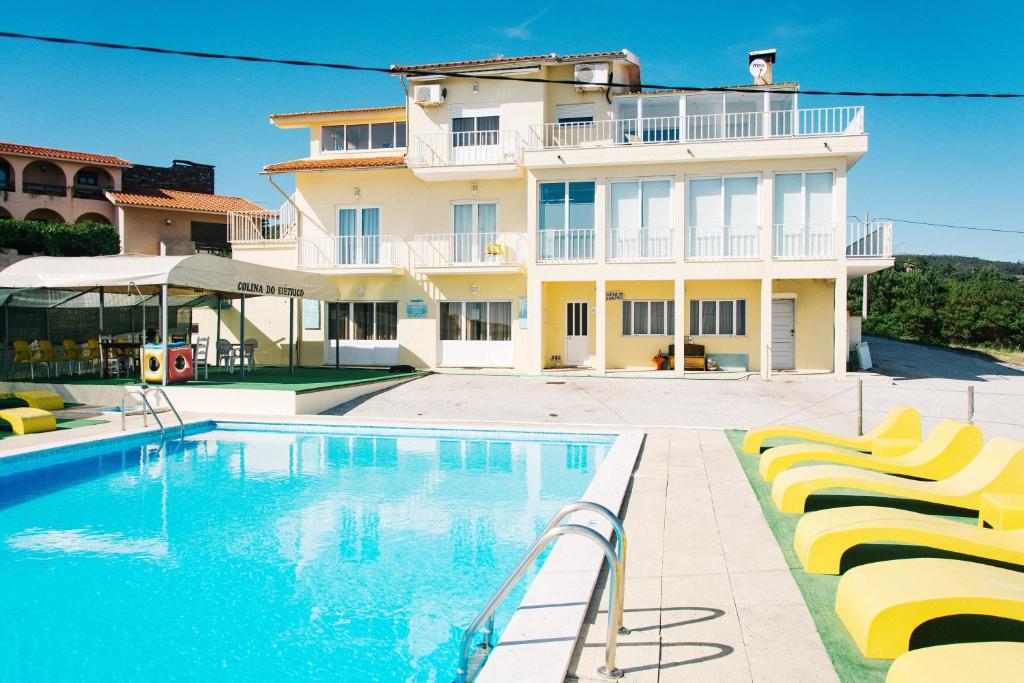 uma casa com piscina em frente a um edifício em Colina do Elétrico em Figueira da Foz