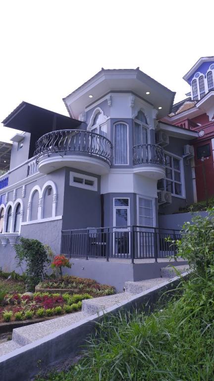 a large white house with a balcony at Villa Dalia Puncak CCC9-26 in Cikujang