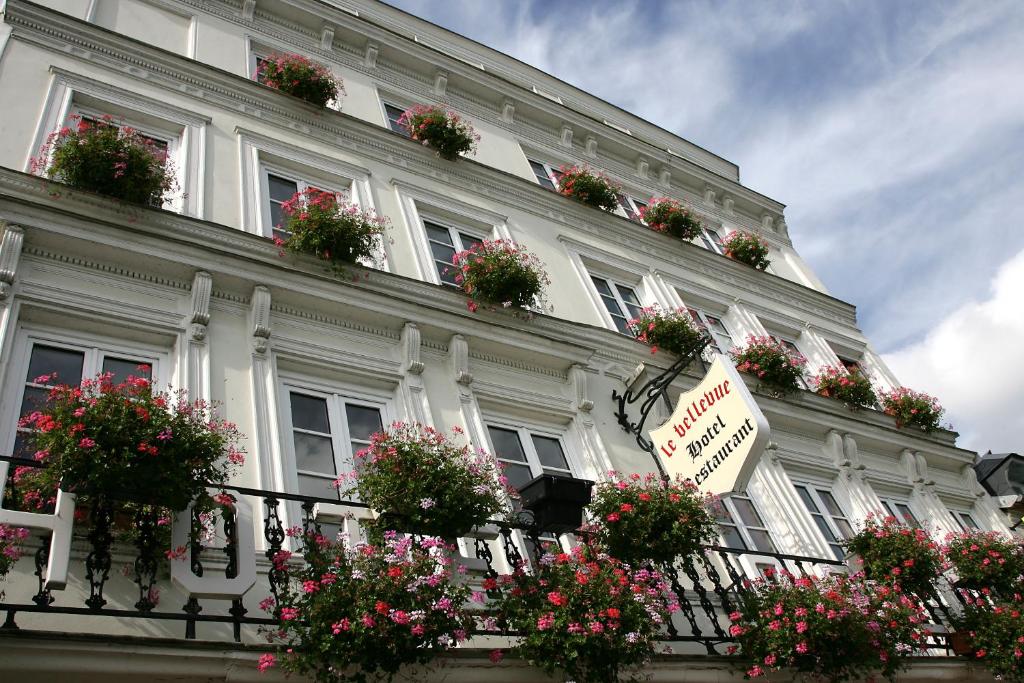 un gran edificio blanco con flores en los balcones en Logis - Hôtel & Restaurant Le Bellevue, en La Bouille