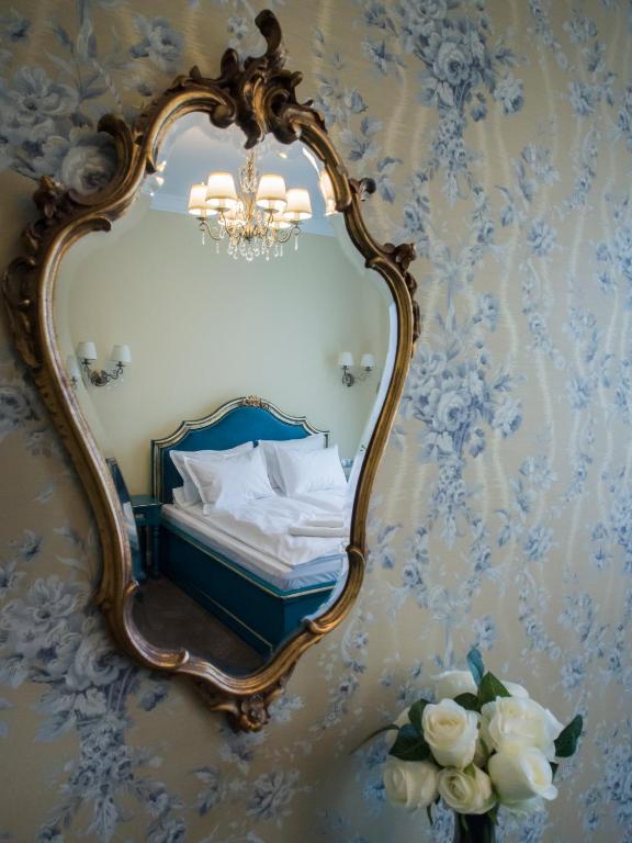 a mirror hanging on a wall with a bed and flowers at Maison Elysée in Sibiu