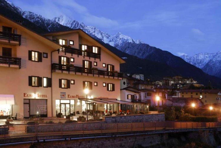 ein großes Gebäude mit Bergen im Hintergrund in der Unterkunft Euro Hotel in Edolo