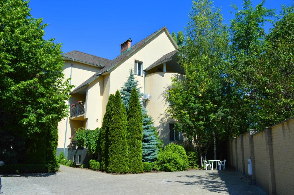 ein weißes Haus mit einem Zaun und einigen Bäumen in der Unterkunft Mini Chisinau Hotel in Chişinău