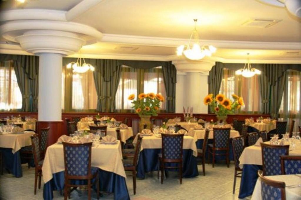 jadalnia ze stołami, krzesłami i kwiatami w obiekcie Hotel Stefano a Melito w mieście Melito di Napoli