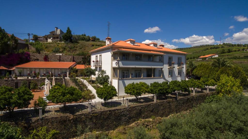 ein weißes Haus mit rotem Dach auf einem Hügel in der Unterkunft Casa de São Domingos in Peso da Régua