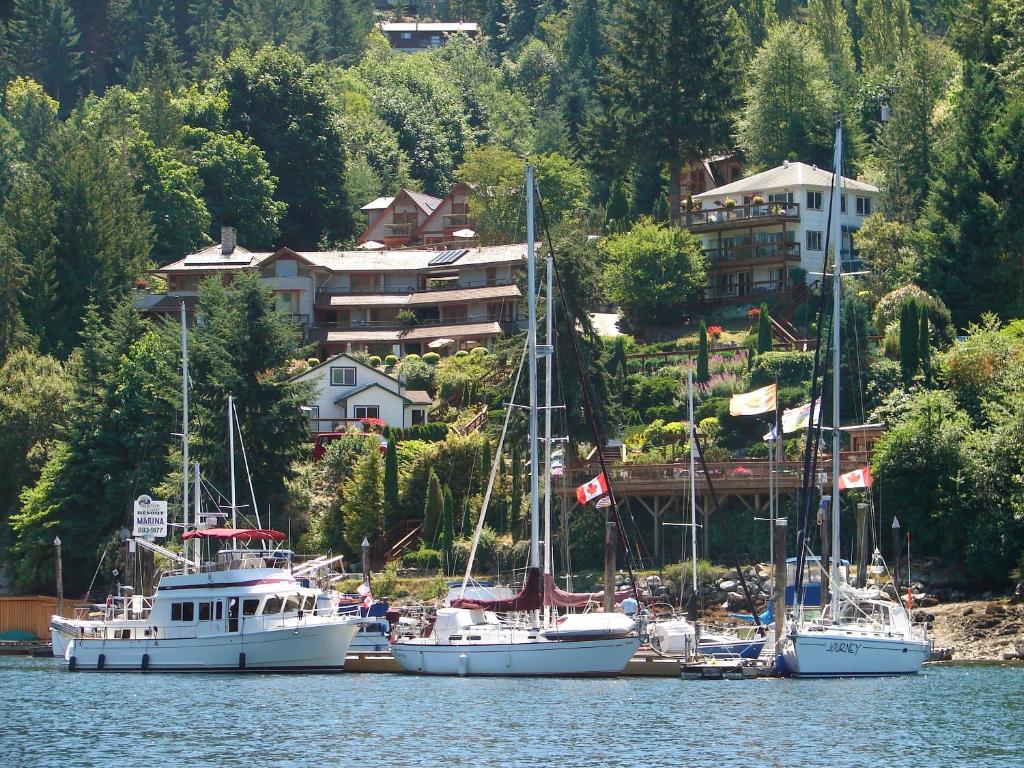 a group of boats docked in a harbor with a house at Sunshine Coast Resort in Madeira Park
