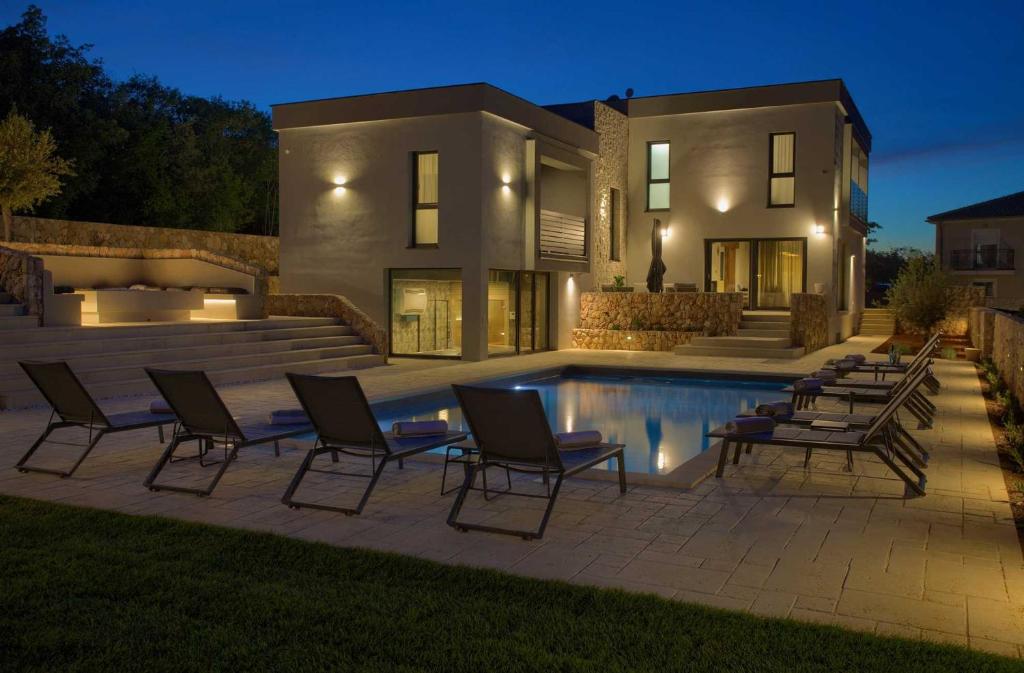 a house with a swimming pool in front of a house at Villa ASTRUM with heated indoor and outdoor pool, jacuzzi and sauna in Vrh