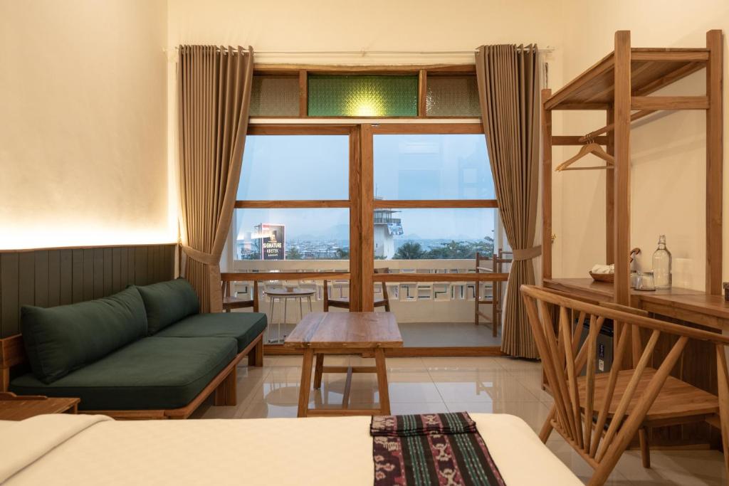 a room with a green couch and a large window at Green Hill Boutique Hotel in Labuan Bajo