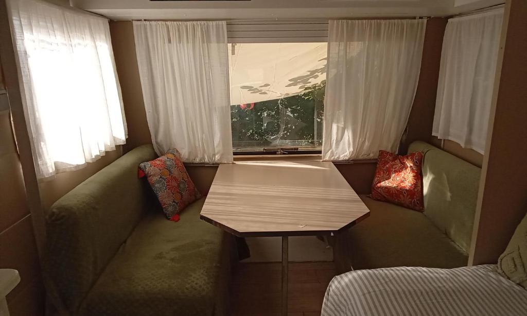 a small room with a table and a couch and a window at La Vintage insolite in Lacaze