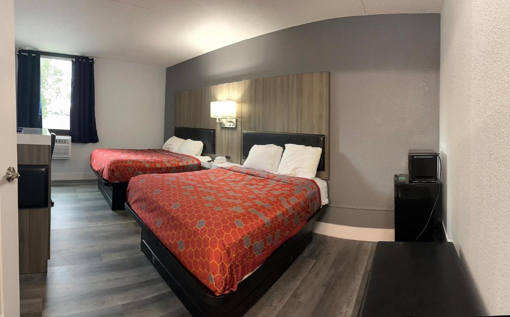 a hotel room with two beds with red sheets at Blue Way Inn and Suites Roseville in Roseville