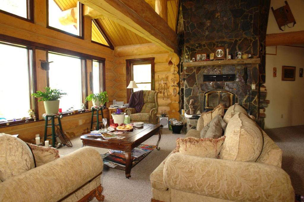 una sala de estar con sofás y una chimenea de piedra. en The Garrison Inn a Montana Bed & Breakfast, en Kalispell