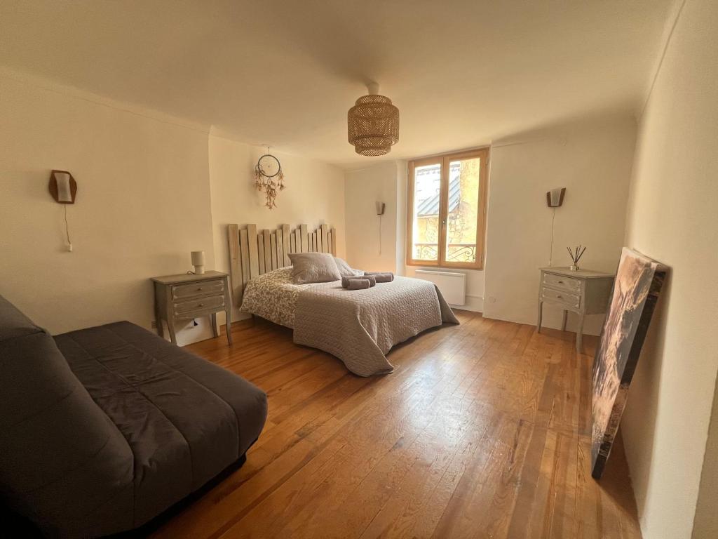 une chambre avec un lit, un canapé et une fenêtre dans l'établissement Maison familiale des remparts, à Colmars