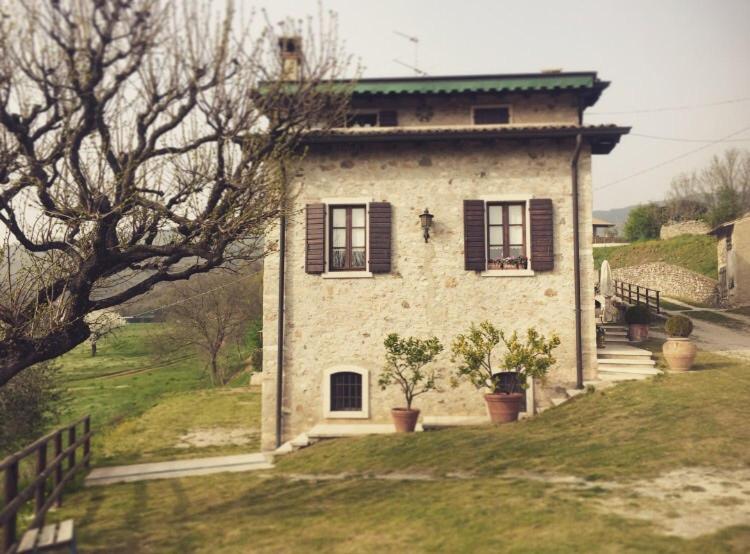 a stone house with black shuttered windows on a hill at Casale Al Solivo B&B in Castion Veronese
