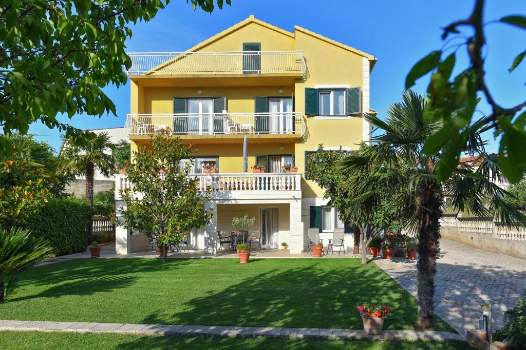 ein gelbes Haus mit einem Balkon und einem Hof in der Unterkunft Villa Slavica 1 in Vodice