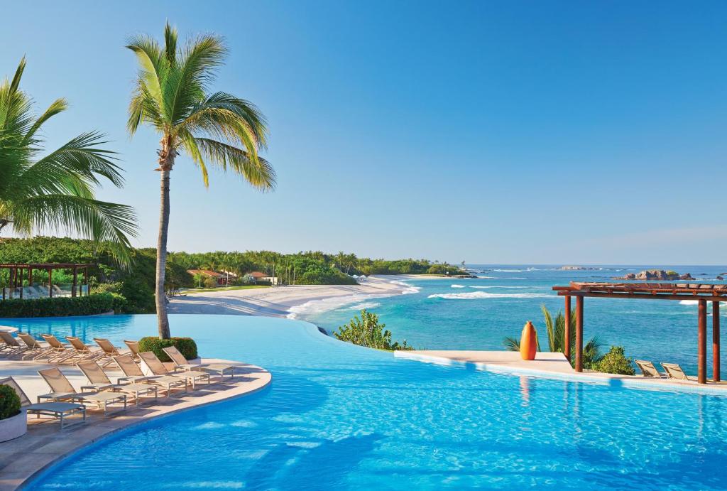 蓬塔米塔的住宿－蓬美達四季度假酒店，海滩旁的游泳池,带椅子和大海