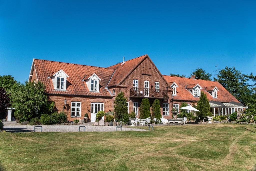 une grande maison en briques rouges avec une cour dans l'établissement Det Gamle Mejeri, à Stokkebro