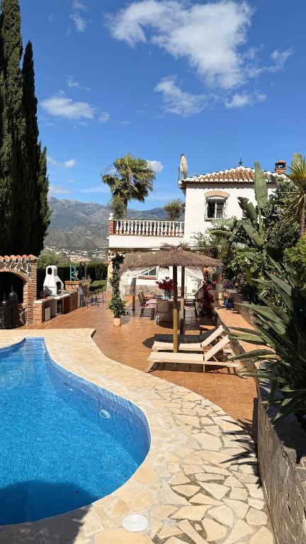 a villa with a swimming pool in front of a house at Boutique Villa Jina, Private Pool, Mountain View, Near Nerja, Quiet Location, Mediterranean Garden in Torrox