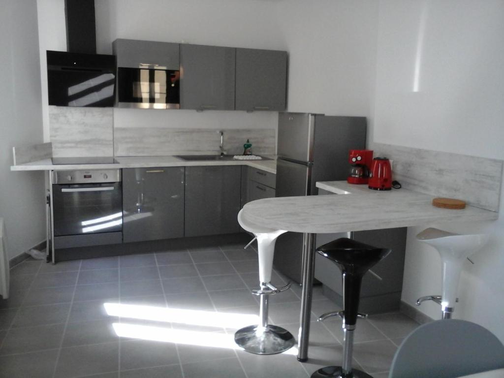 cocina con mesa y electrodomésticos de acero inoxidable en Colombe, en LʼIsle-sur-la-Sorgue