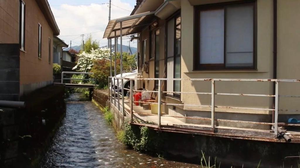 a house sitting on a canal next to a house at guesthouse Emi 笑み NIKKO in Nikko