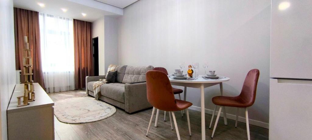 a living room with a couch and a table and chairs at Luxury new apartment in the downtown in Bishkek