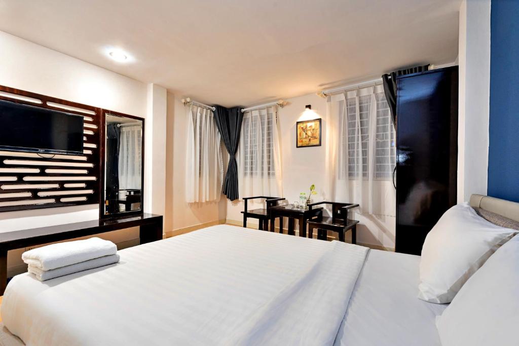 a bedroom with a large white bed and a table at S79 Residences SEN in Ho Chi Minh City