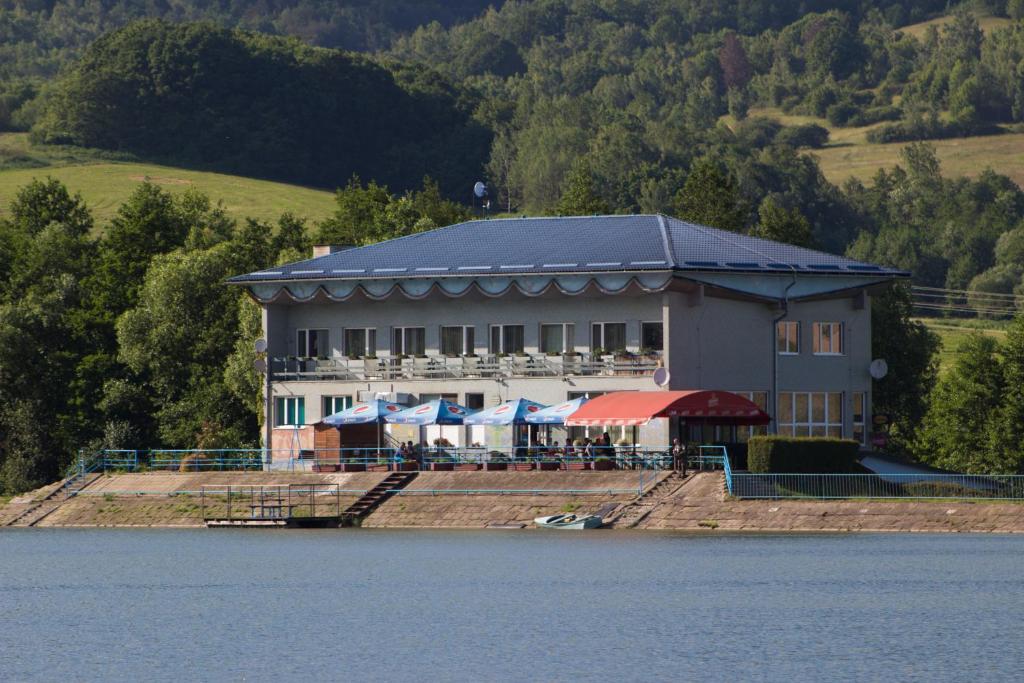 a large building on the side of a lake at Penzion Flipper in Revúca