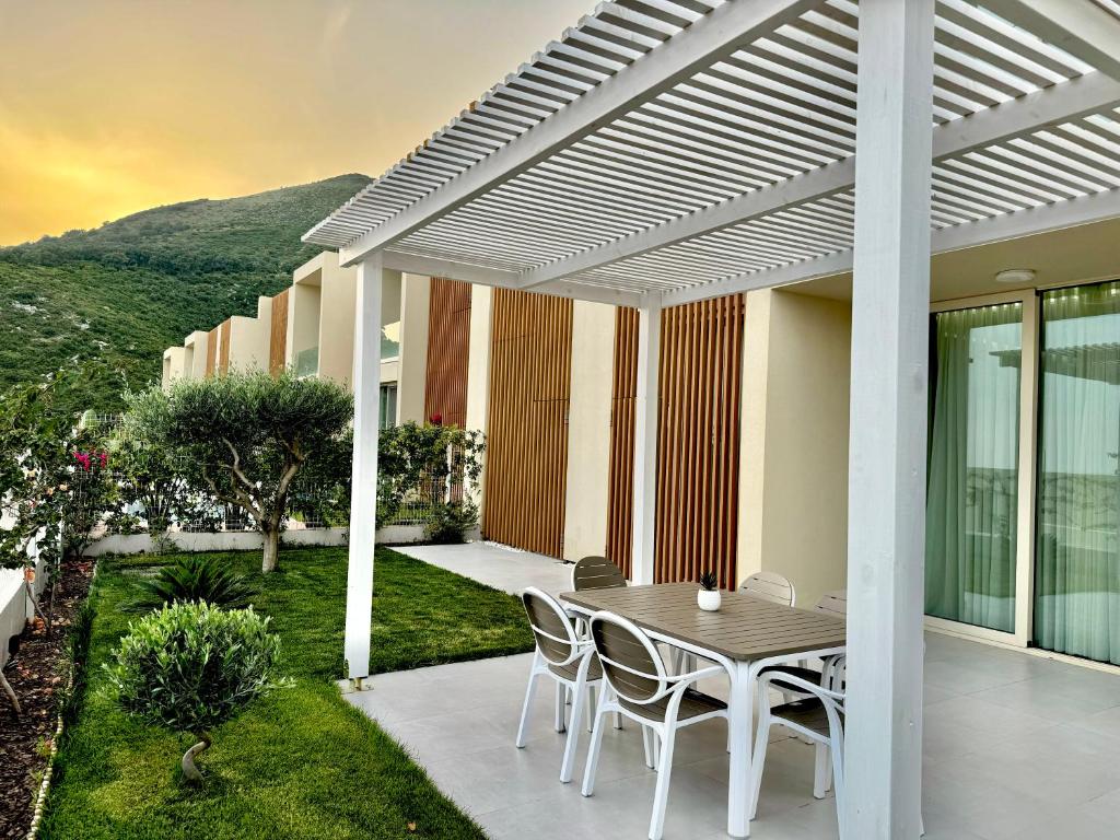 a patio with a table and chairs under a pergola at Olive Garden Villa in Himare