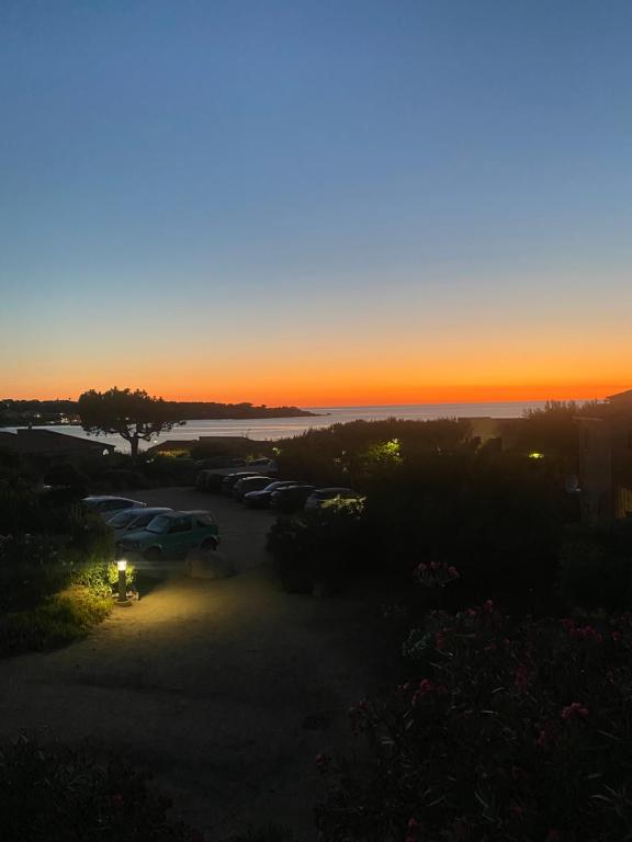 a sunset over a parking lot with cars parked at Trilocale vista mare in Lumio
