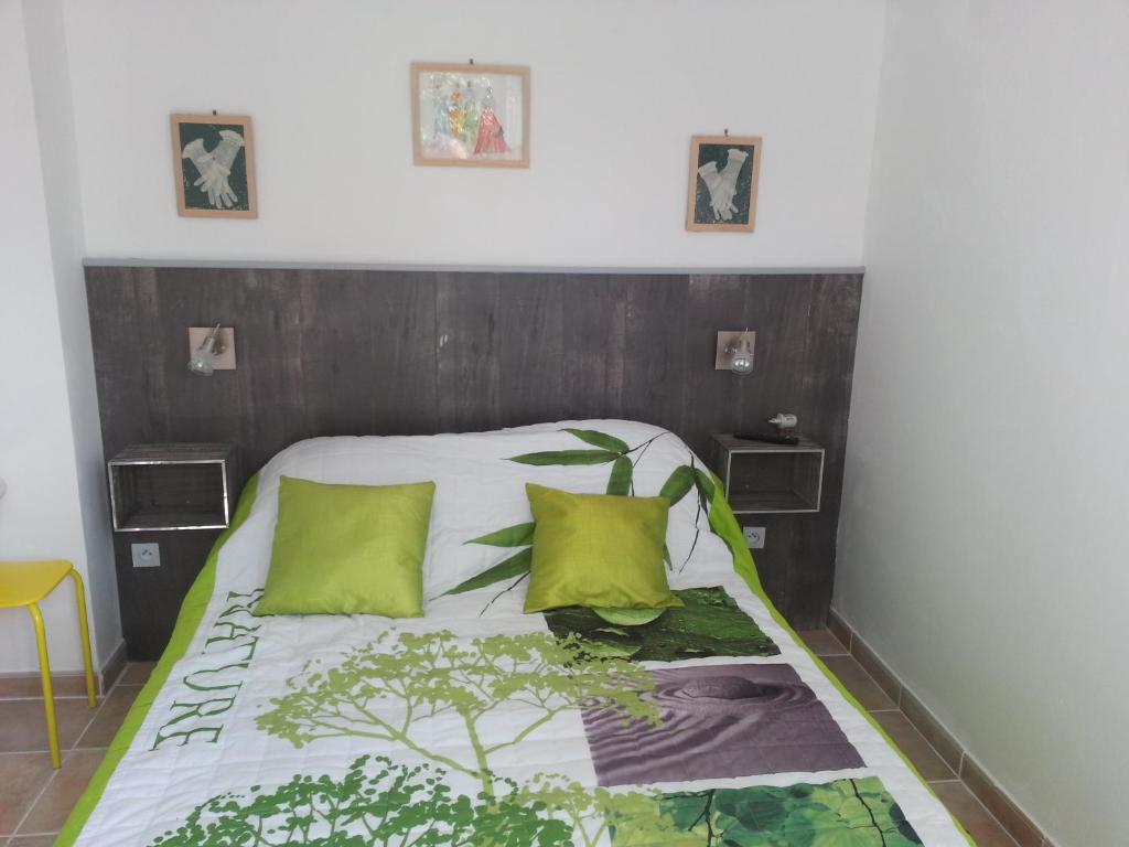 - un lit avec une tête de lit en bois et 2 oreillers verts dans l'établissement Berne &Michel, à Montfavet