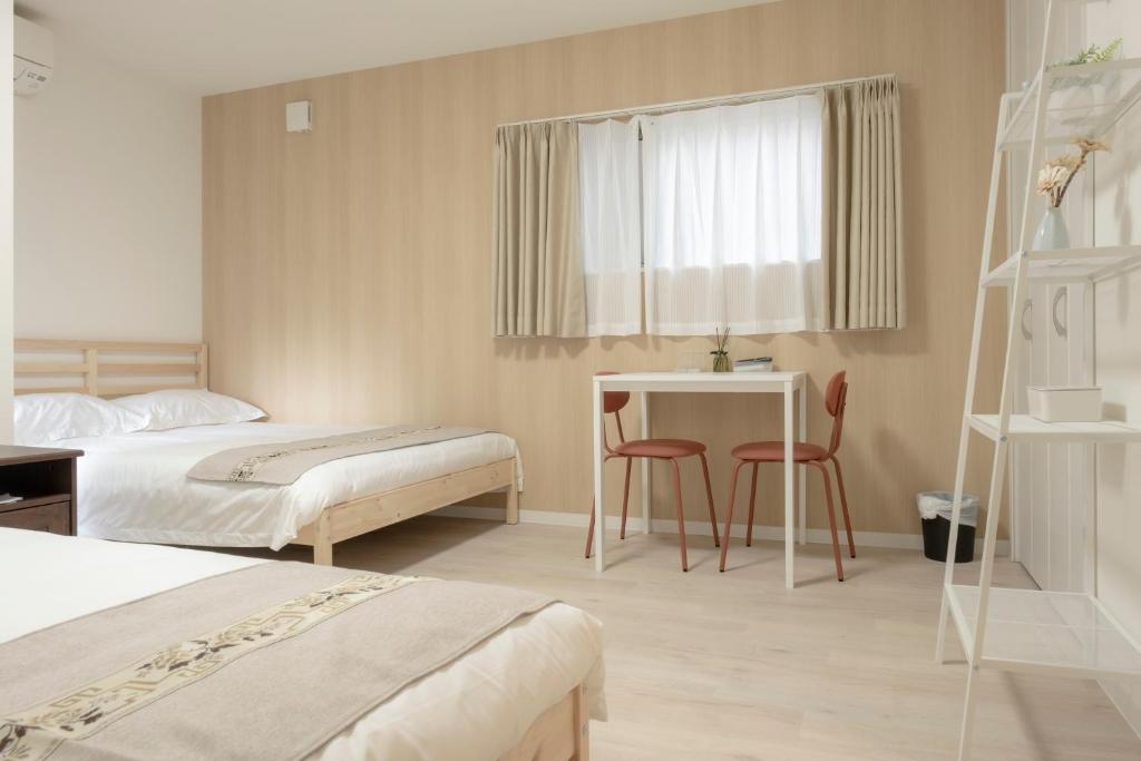 a hotel room with two beds and a table and chairs at GuesthouseA in Osaka