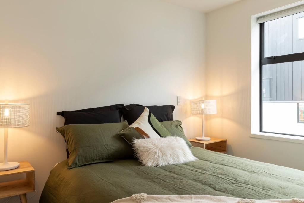 a bedroom with a green bed with two lamps at Luxury Apartment Christchurch Central in Christchurch
