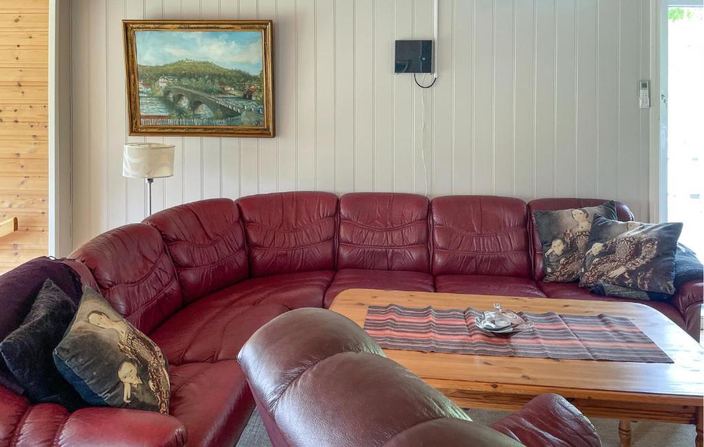 a living room with a red leather couch with a coffee table at 4 Bedroom Beautiful Home In Grovfjord in Grovfjord
