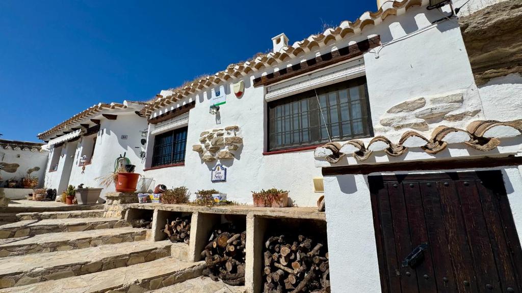 a white house with a wooden door and stairs at Cueva Solaz Galera in Galera
