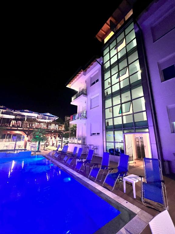 ein Schwimmbad mit blauen Stühlen neben einem Gebäude in der Unterkunft Brian Hotel in Velipojë
