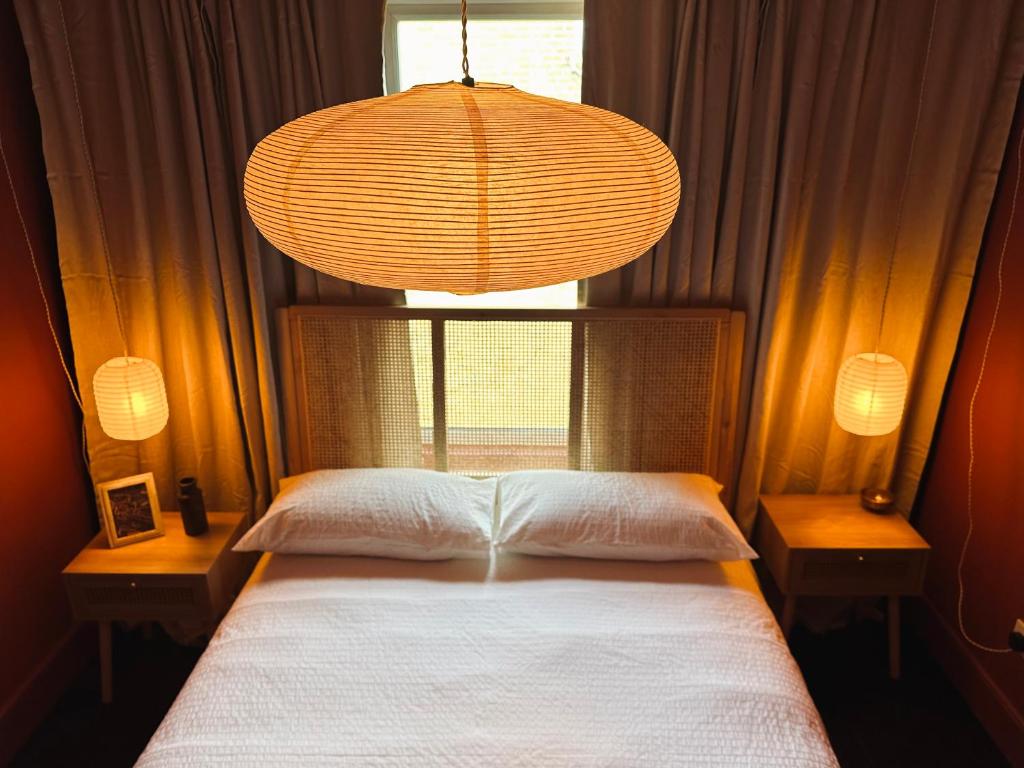 a bedroom with a bed with a window and a chandelier at Margate Manor - Rooms by the Sea in Margate