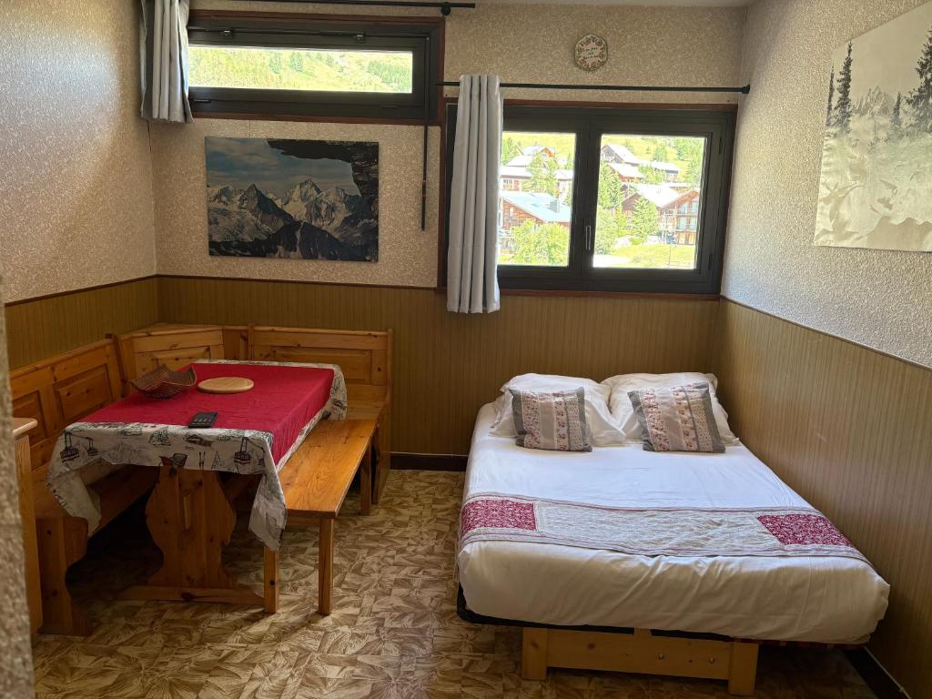 a room with two beds and a table and two windows at Studio Centre Vars Le Seignon in Vars