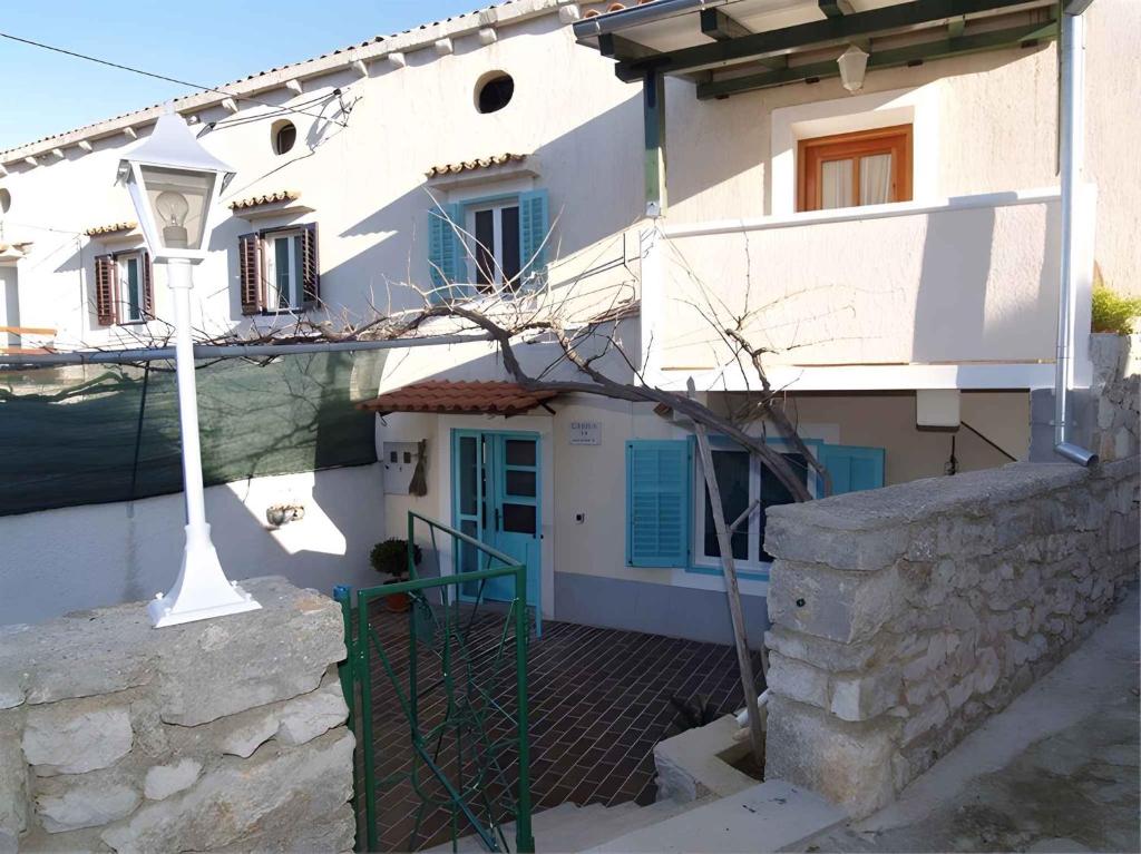 a white house with a blue door and stairs at Apartments in Veli Losinj 33624 in Sveti Nicola
