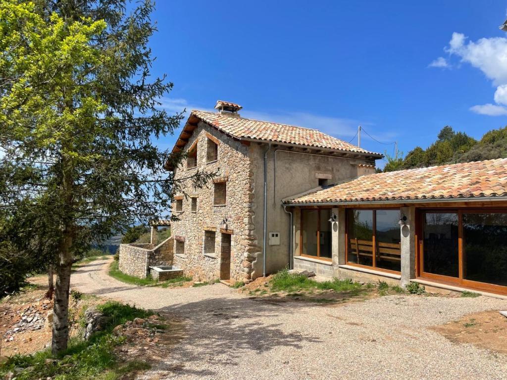 an old stone house with a large window at Poble Rural Puig Arnau - Pubilló in Oden