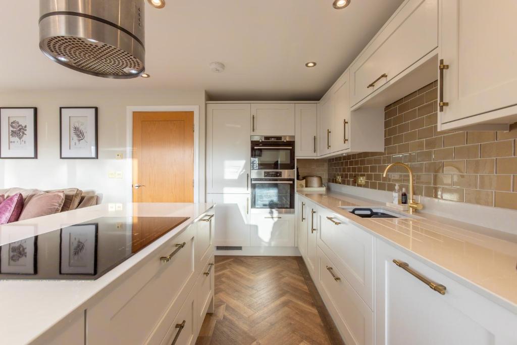 a kitchen with white cabinets and a counter top at Beech Meadow-Home from Home Luxury Holiday Cottage in Kirkby Lonsdale