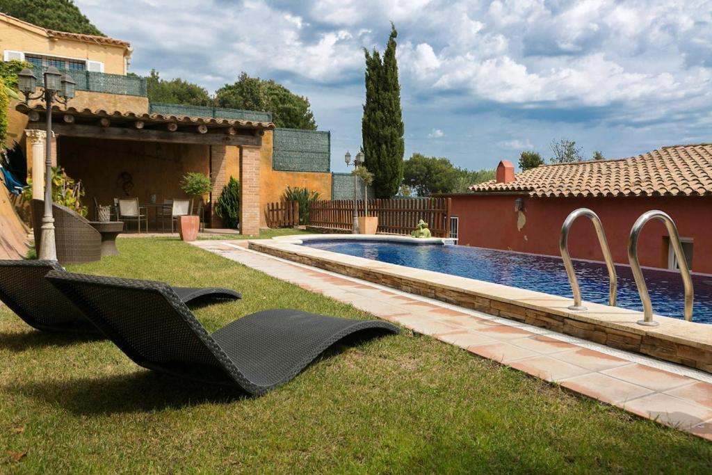 a yard with a swimming pool and a black chair at 3 bedroom villa close to the center with private pool & garden H30 in Begur